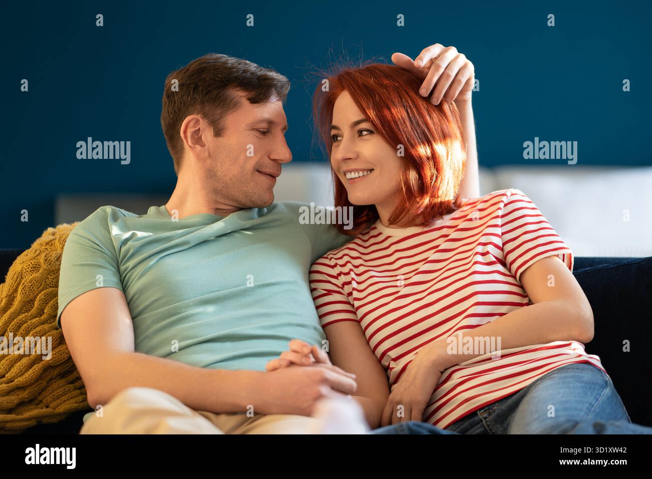 Le coppie sposate amorevoli si guardano l'un l'altro tenendosi per mano condividono sentimenti sinceri sul divano di casa Foto Stock