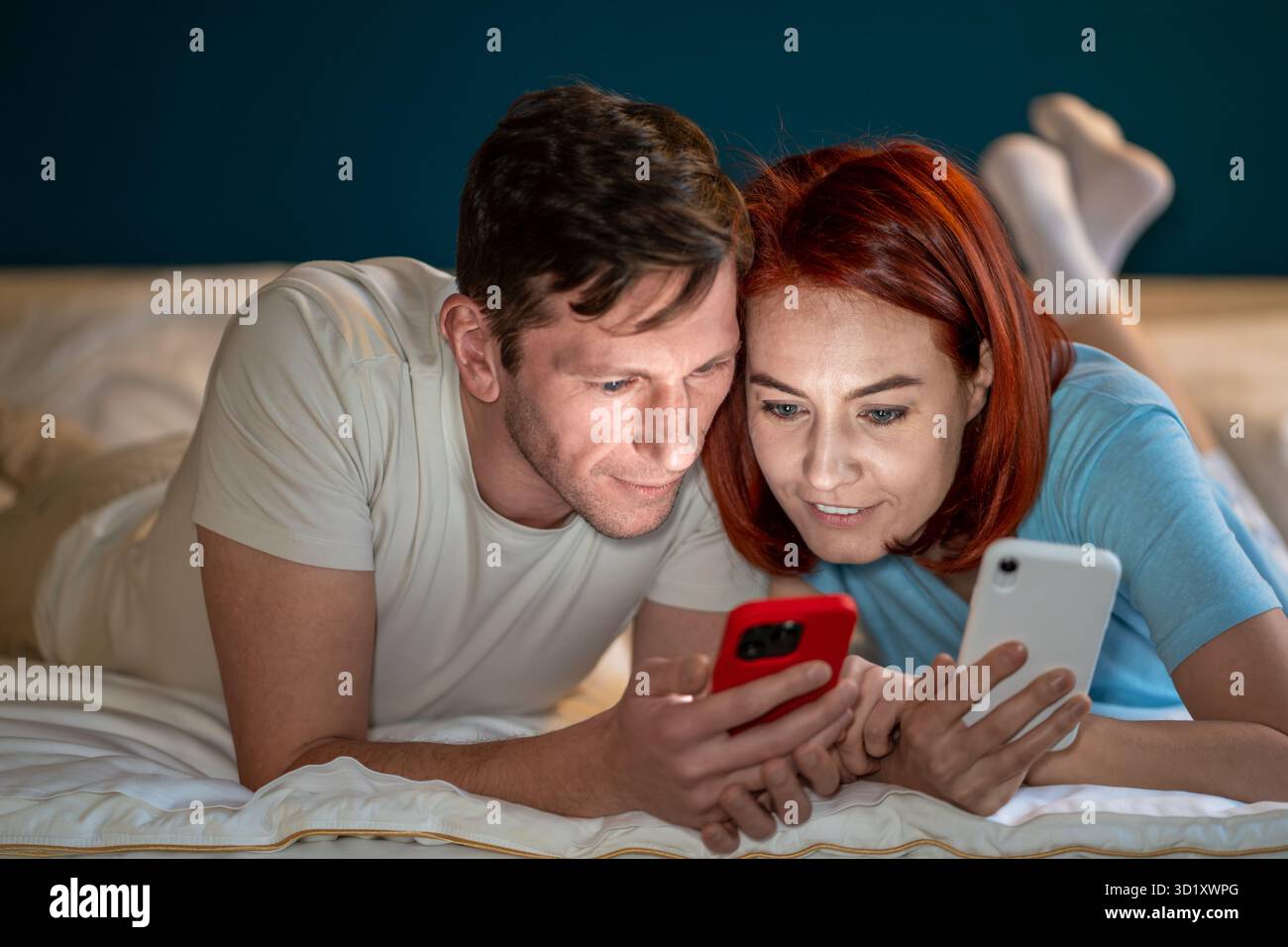 Le coppie sposate usano i telefoni insieme per guardare video interessanti e affascinanti. Tempo libero in comune Foto Stock