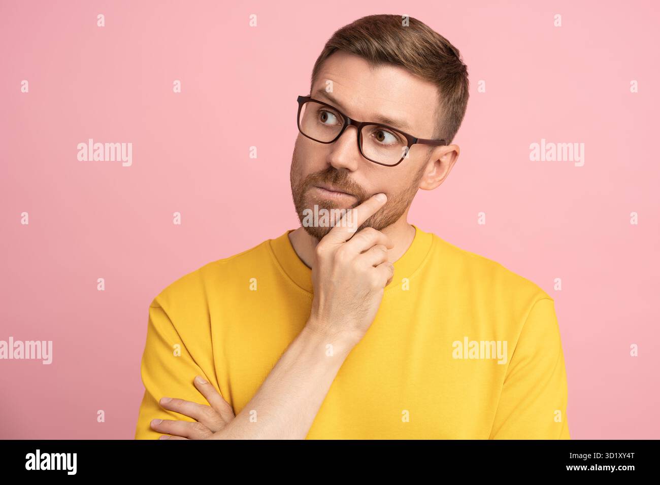 L'uomo perplesso pensa di guardare lontano toccando la mano sul mento e prendendo decisioni sulla parete dello studio Foto Stock