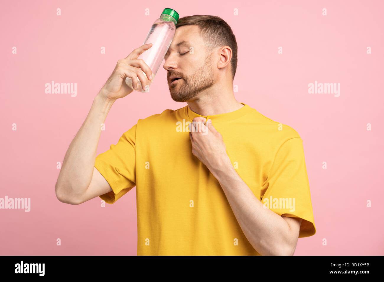 L'uomo stanco soffre di calore e pressione sanguigna, mette bottiglia di acqua fredda sulla fronte, sente sete Foto Stock