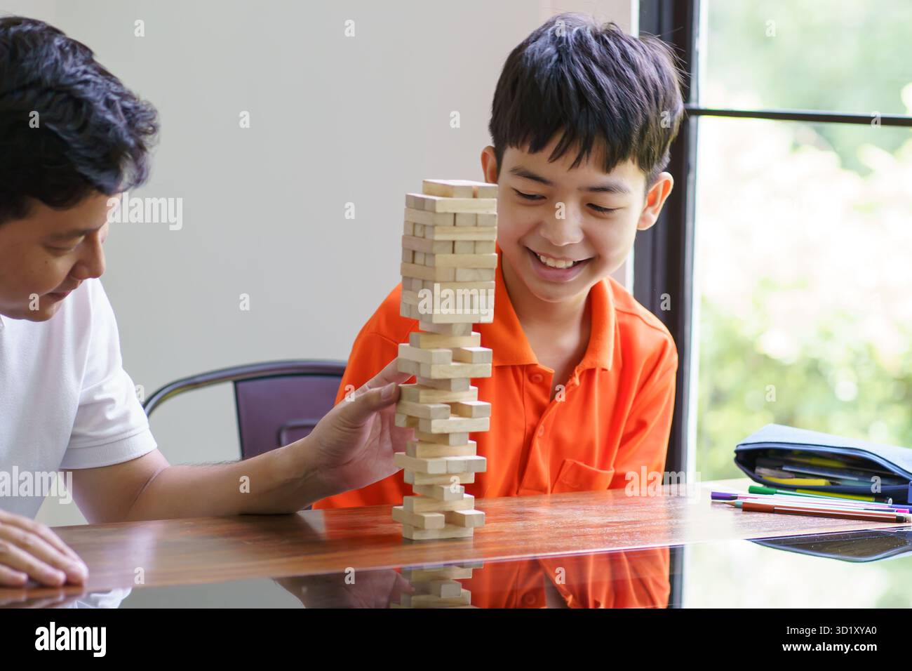 Padre e figlio asiatici che giocano a blocchi di legno bambino Carefree che gioca a blocchi di legno costruttore di costruzioni di blocchi di legno da blocchi con padre Foto Stock