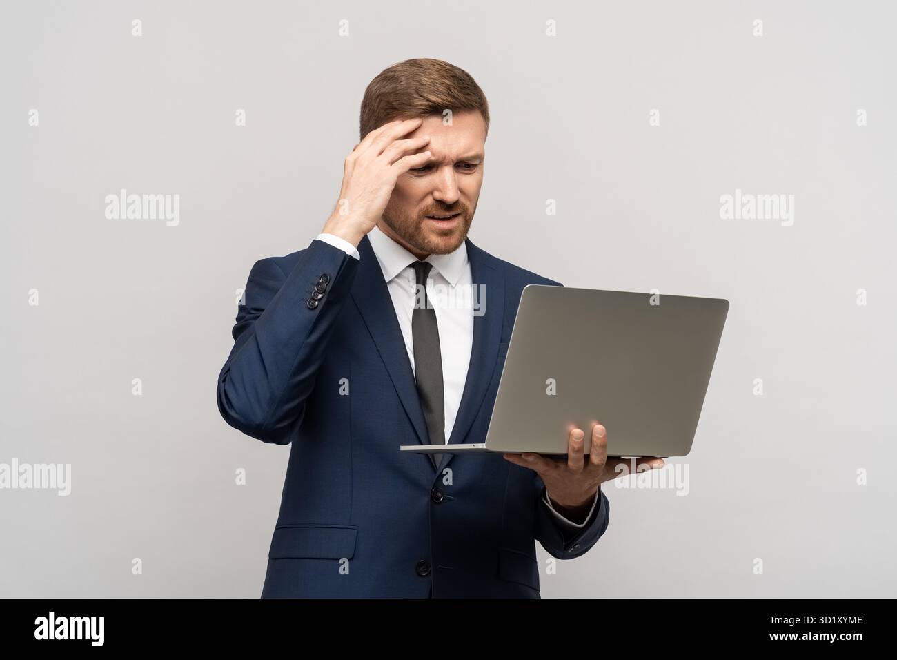 L'uomo ha problemi negli affari, scarsi risultati finanziari guardando il notebook su sfondo grigio. Foto Stock