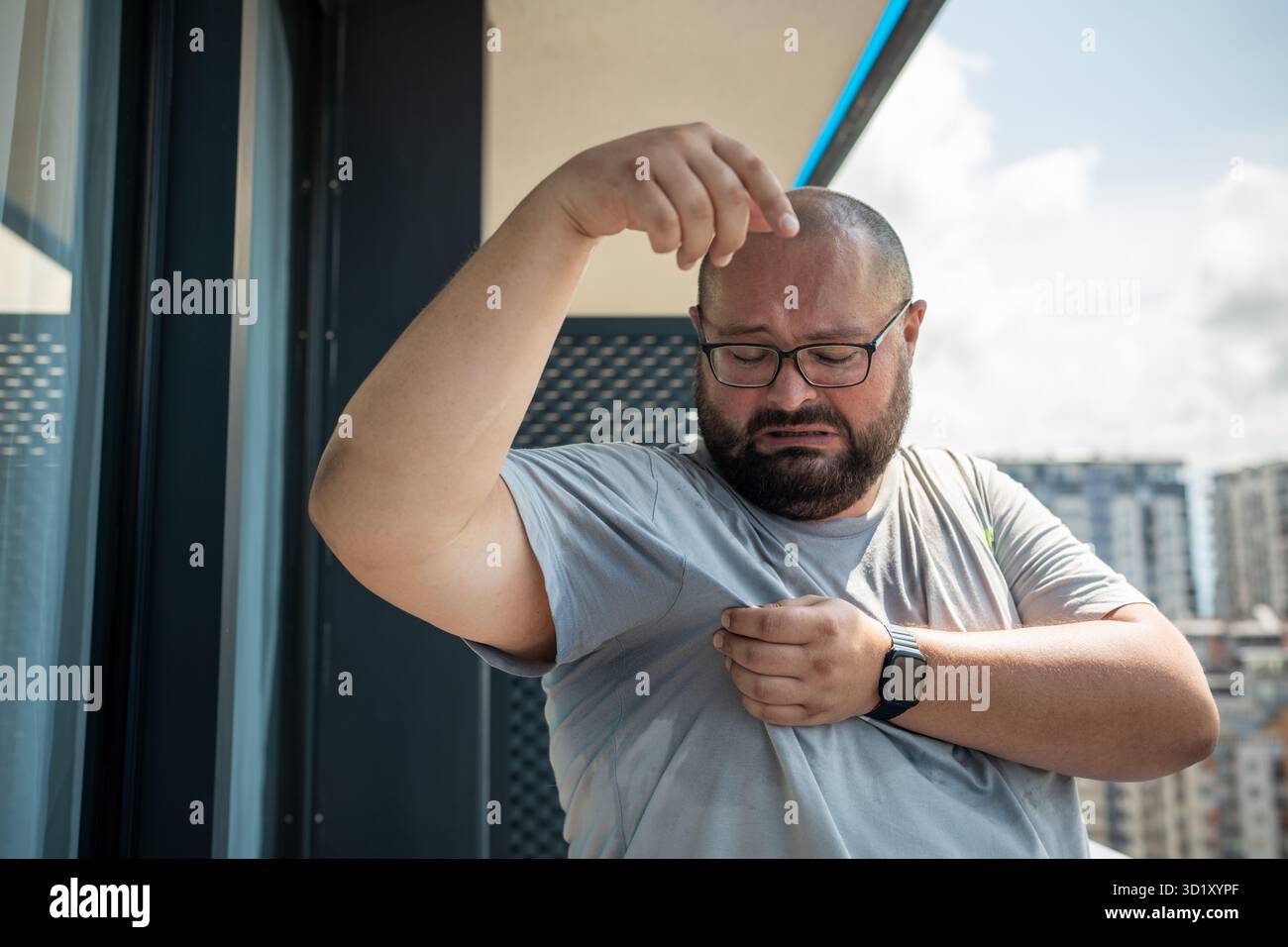 Uomo grasso con ascelle bagnate ed espressione disgustata sul viso. Clima umido e temperatura dell'aria elevata Foto Stock