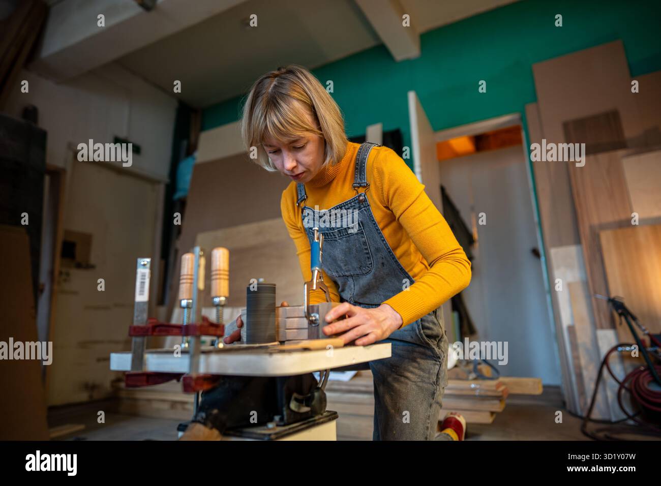 Una donna incentrata falegname trasforma prodotti artigianali in legno su tornio per piccole imprese. Foto Stock