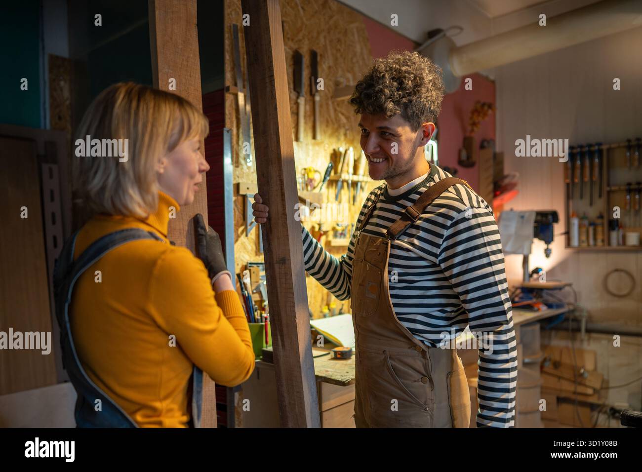 Officina di falegnameria, artigiani che lavorano insieme. Carpentieri che chiacchierano tra una creazione e l'altra Foto Stock