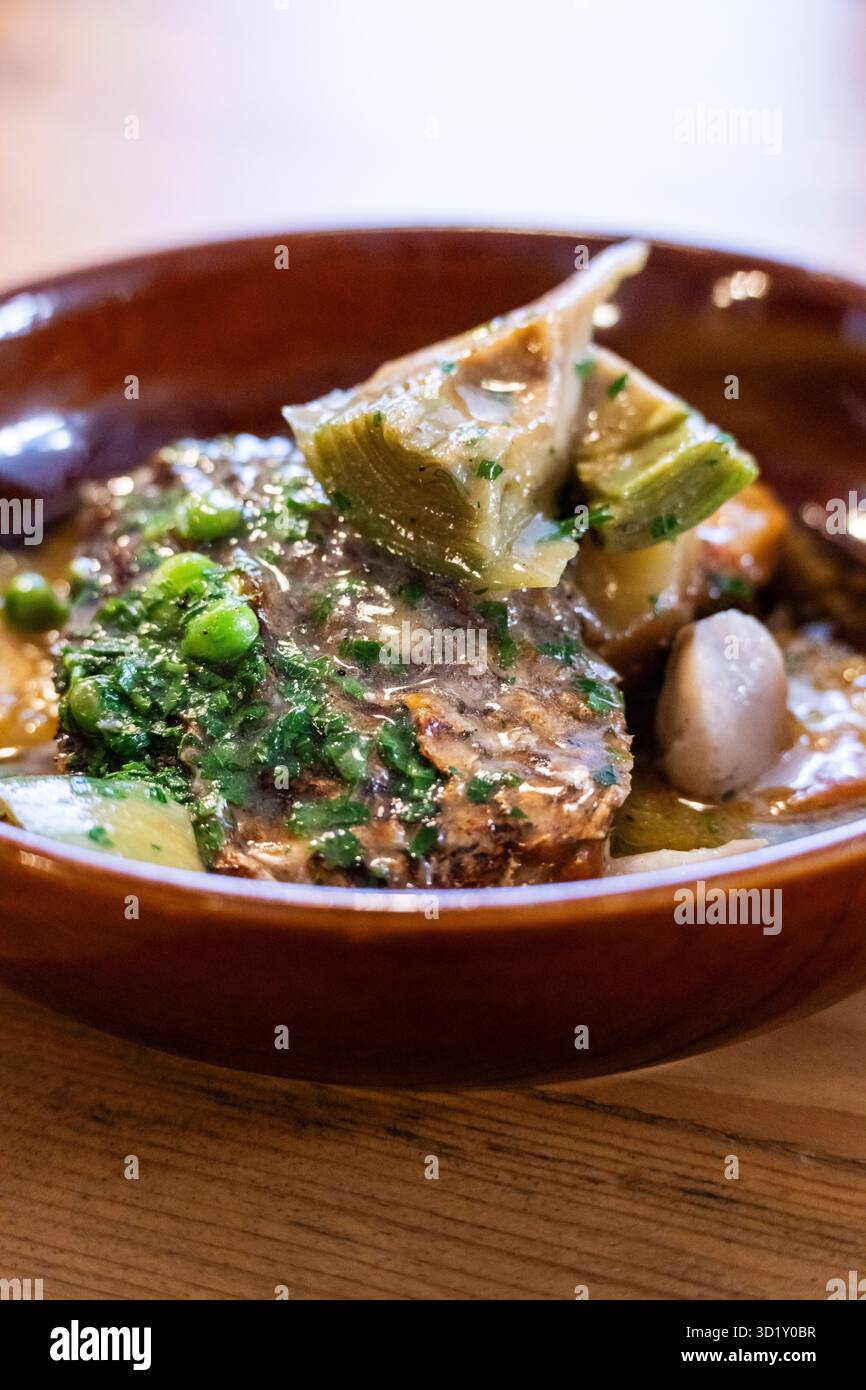 Corvina in salsa verde con carciofi e patate tinar Foto Stock