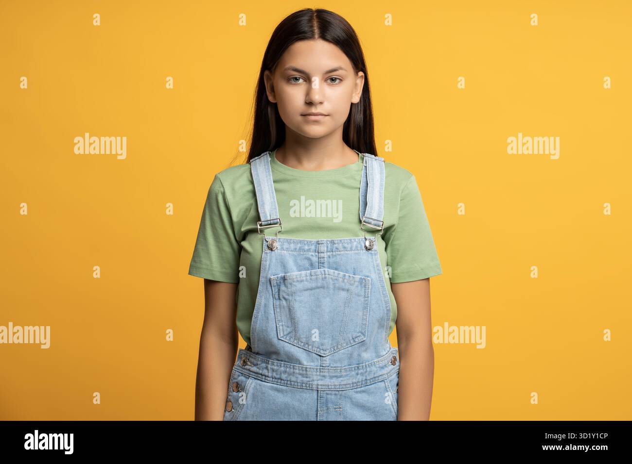 Studentessa intelligente con uno sguardo non emotivo isolato su sfondo arancione che guarda la fotocamera Foto Stock