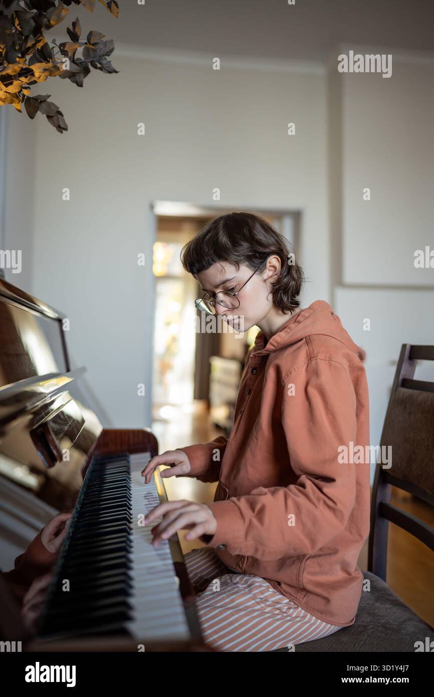 Pianista studentessa che pratica la musica suonando il pianoforte a casa, potenzia le tue abilità di pianoforte Foto Stock