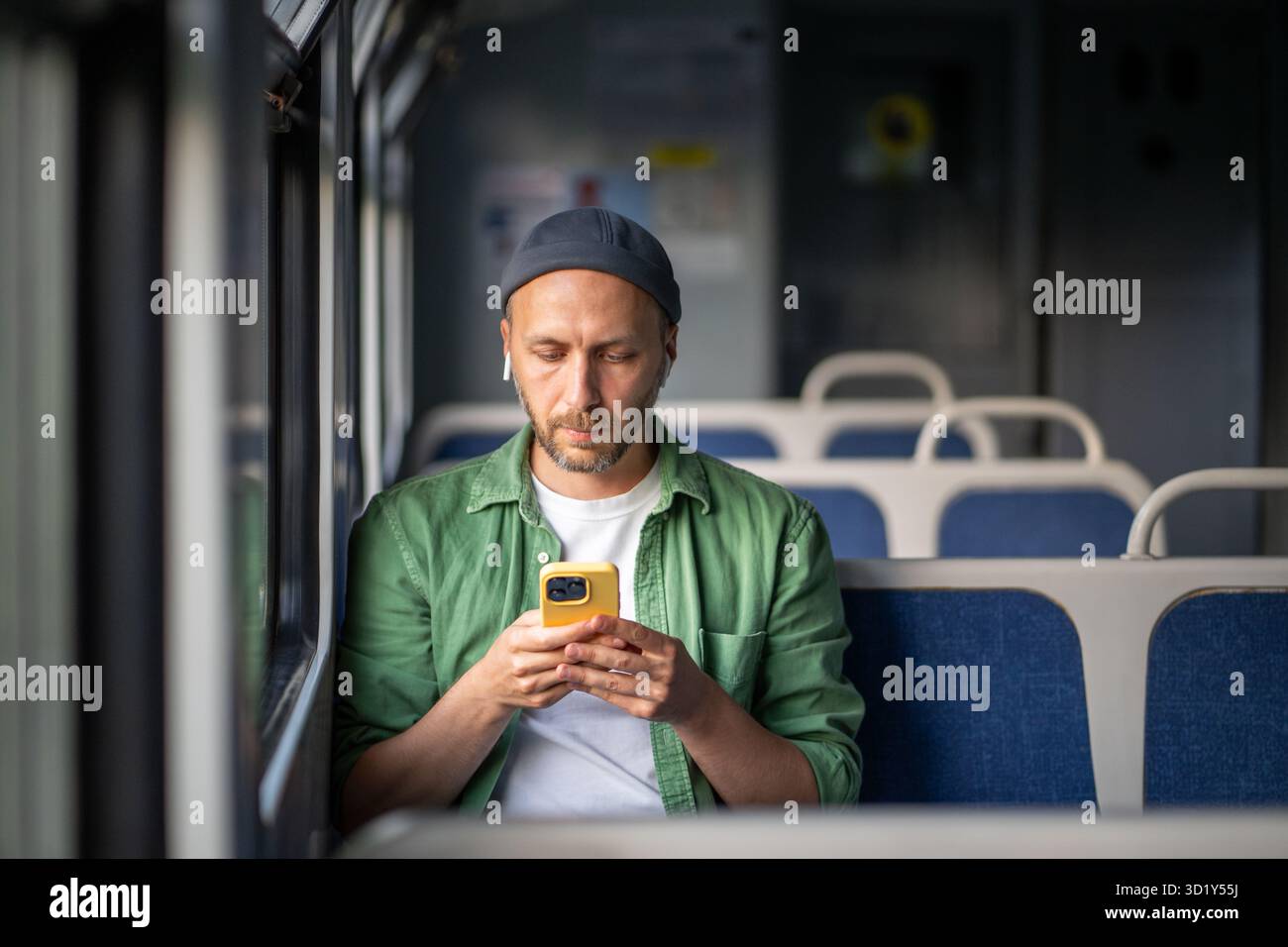 Il pendolare attento ascolta contenuti audio sullo smartphone tramite auricolari, siediti mentre sei in viaggio per il lavoro Foto Stock