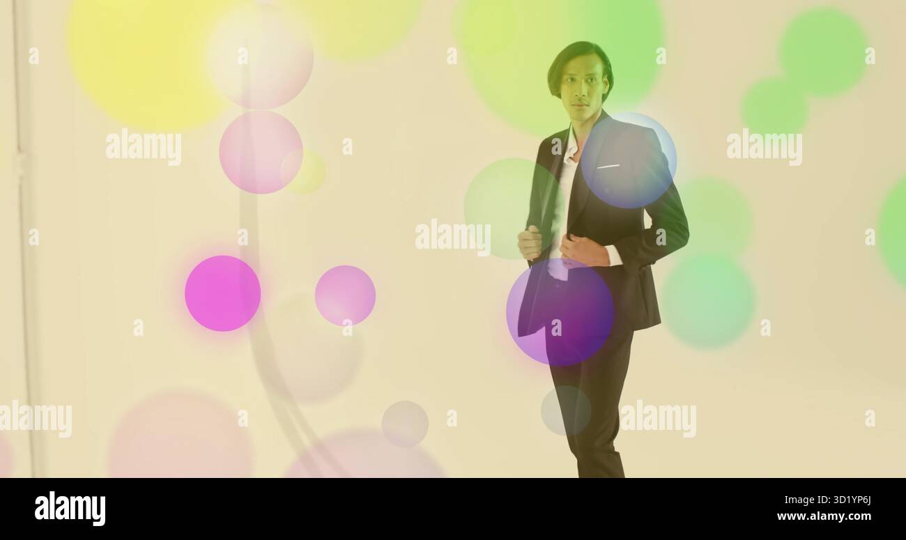 Modello regolabile con giacca nera, pantaloni in studio con cerchi colorati e clip per microfono Foto Stock