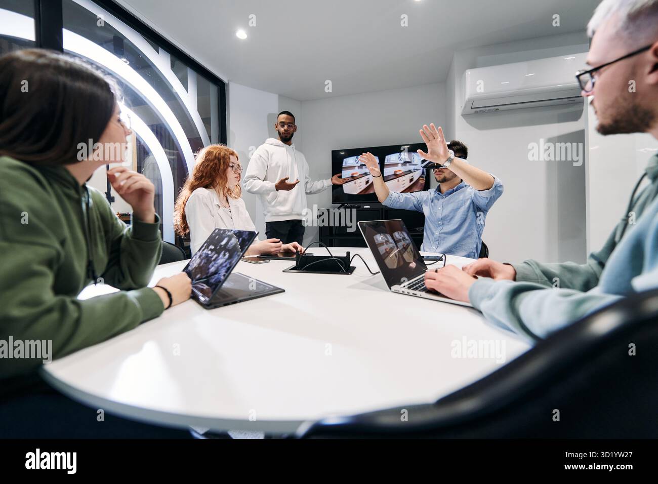 Un gruppo eterogeneo di uomini d'affari collabora e testa una nuova tecnologia di realtà virtuale, indossando occhiali virtuali, mostrando inno Foto Stock