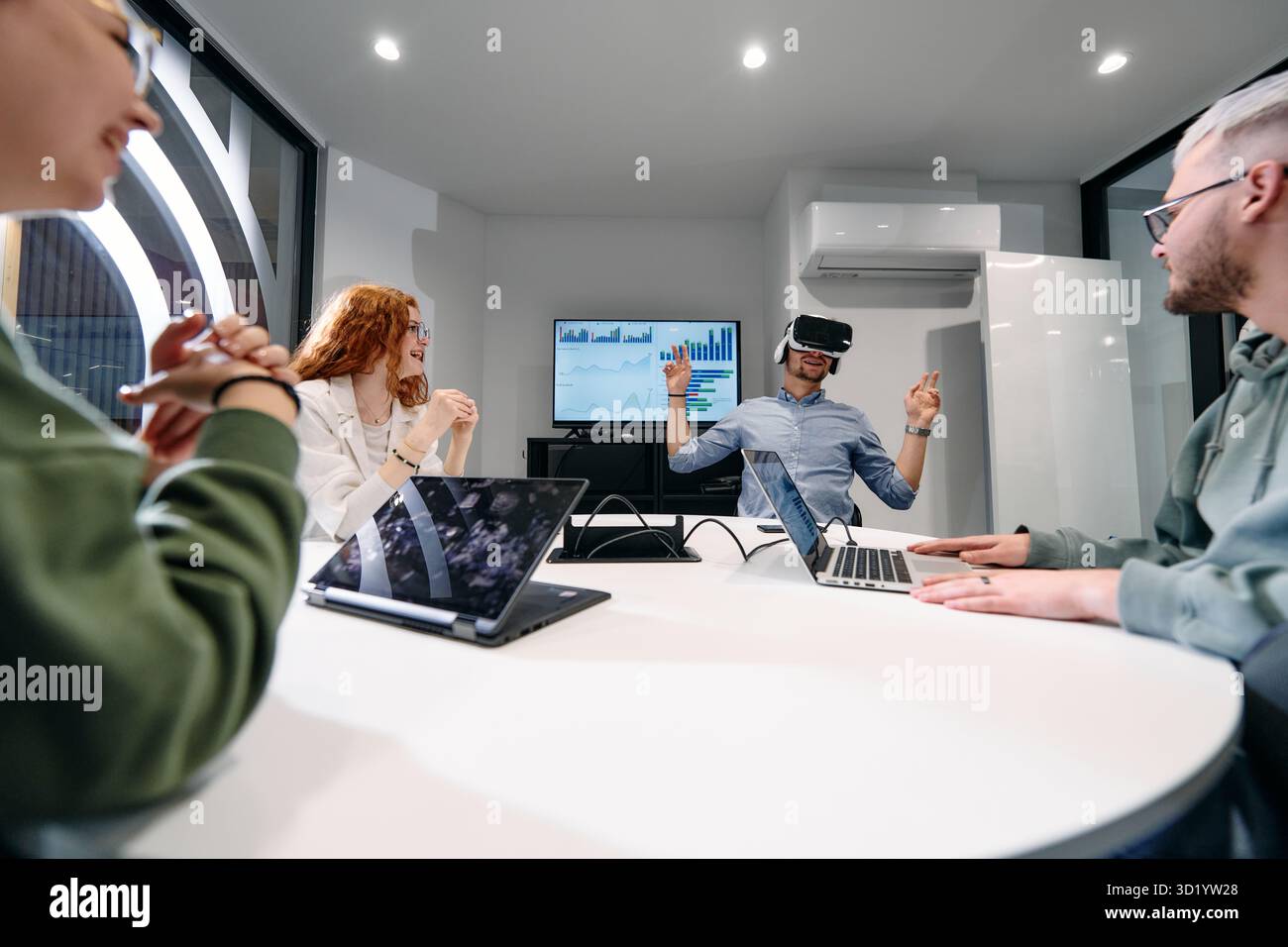 Un gruppo eterogeneo di uomini d'affari collabora e testa una nuova tecnologia di realtà virtuale, indossando occhiali virtuali, mostrando inno Foto Stock