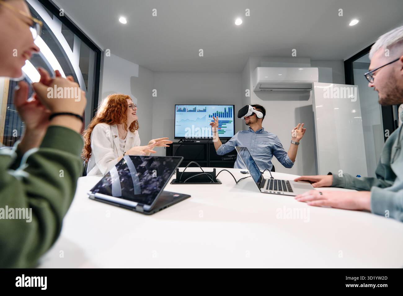 Un gruppo eterogeneo di uomini d'affari collabora e testa una nuova tecnologia di realtà virtuale, indossando occhiali virtuali, mostrando inno Foto Stock