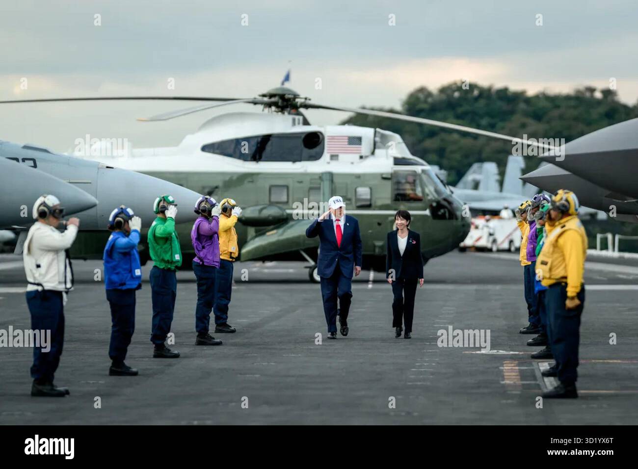 Il presidente Donald Trump e il primo ministro giapponese Sanae Takaichi esaminano il personale navale statunitense e giapponese a bordo della USS George Washington presso la base navale di Yokosuka, in Giappone, il 28 ottobre 2025. Un elicottero dei Marine degli Stati Uniti è visibile sullo sfondo come parte della cerimonia di arrivo. Per gentile concessione della Casa Bianca. Foto Stock