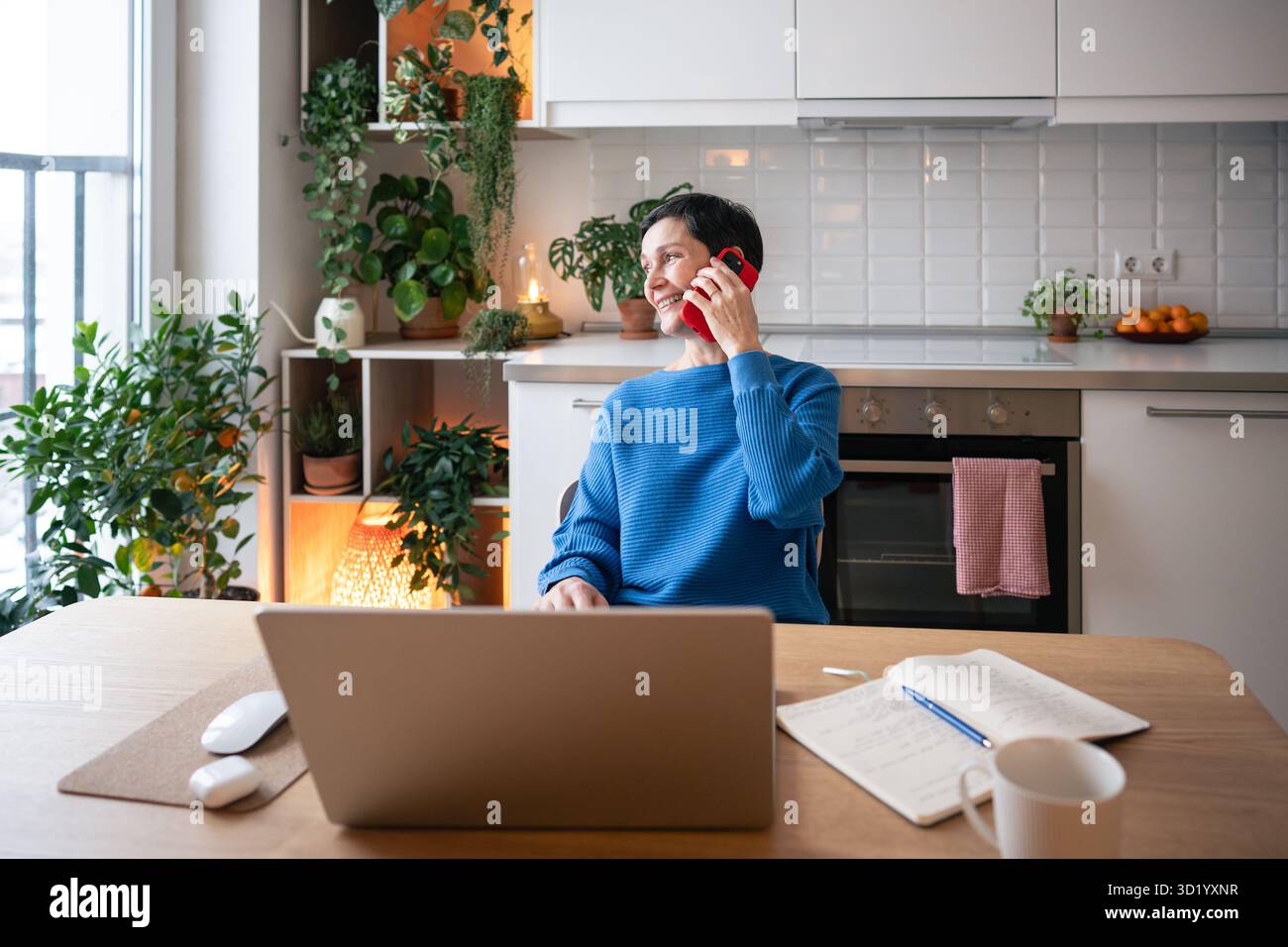 Estrusione remota. Donna sorridente che gestisce progetti freelance con telefonate e laptop nell'ufficio domestico Foto Stock