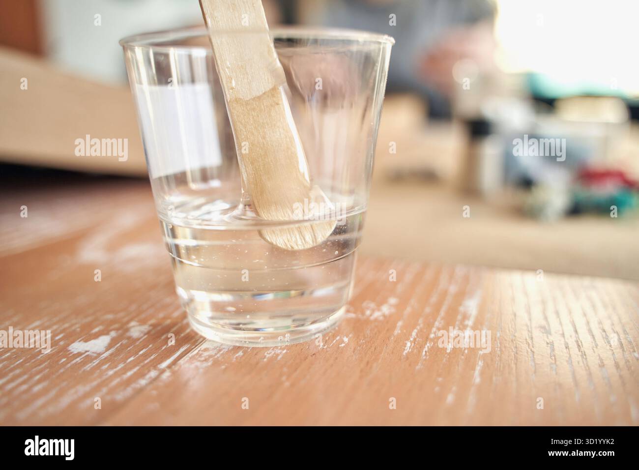 Tazza in plastica trasparente con bastoncino di agitazione su una superficie in legno in un ambiente ben illuminato. Foto Stock