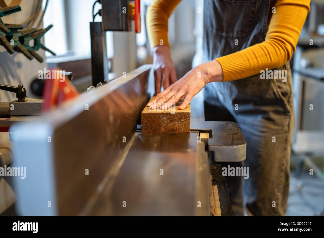 L'artigiana lavora a mano utilizzando una pialla elettrica, modellando il legno in pezzi lisci per progetti di mobili Foto Stock