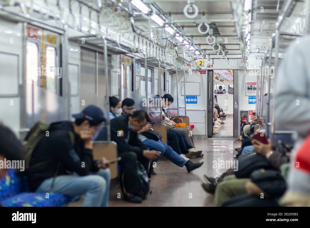 Giacarta, Indonesia - 10 agosto 2025: Vista interna di un treno pendolare con varie persone sedute sul treno Foto Stock
