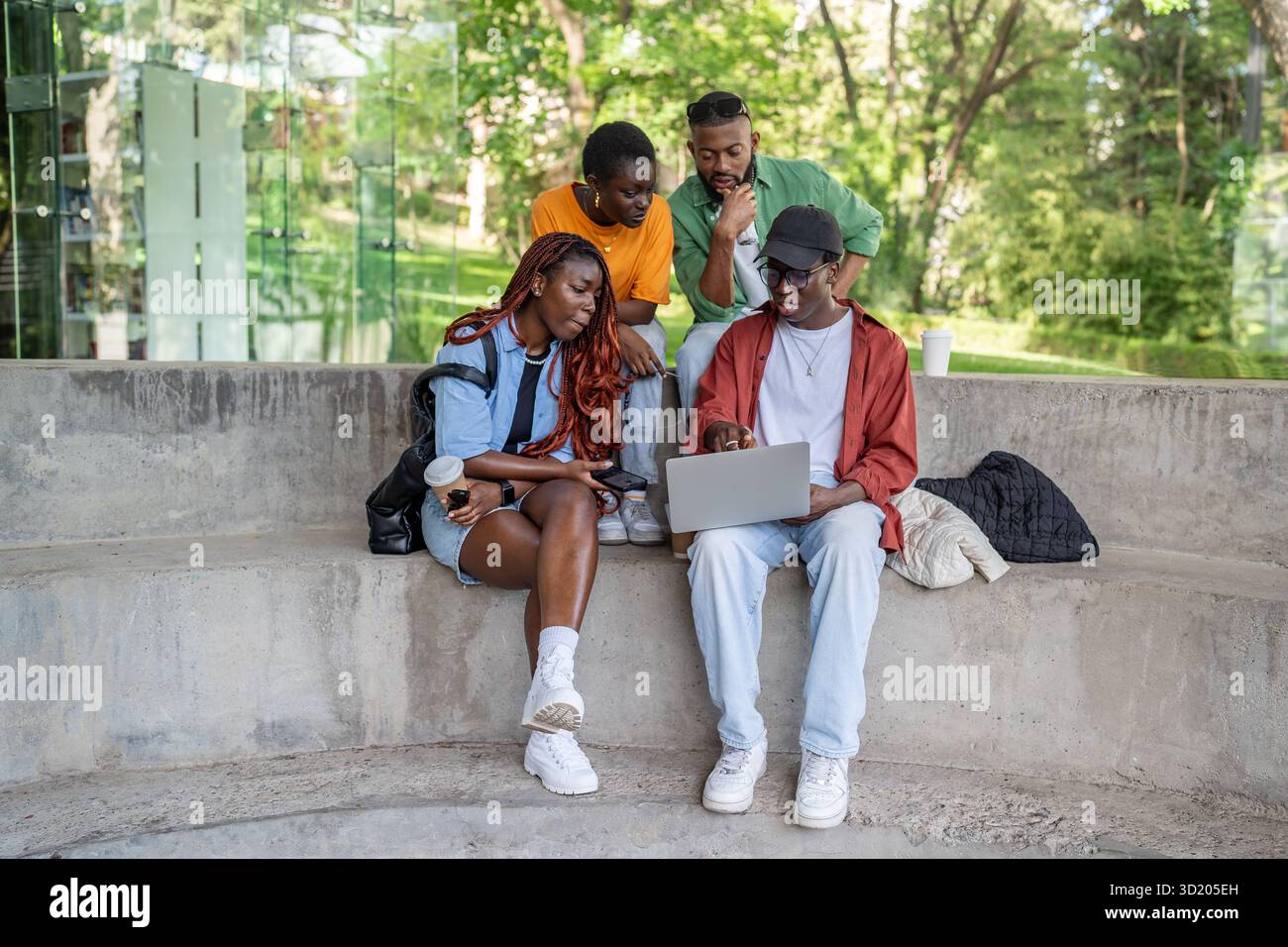 Gli amici studenti di colore lavorano su un computer portatile alla panchina del parco. Collaborazione progettuale, freelance, incontro di startup Foto Stock