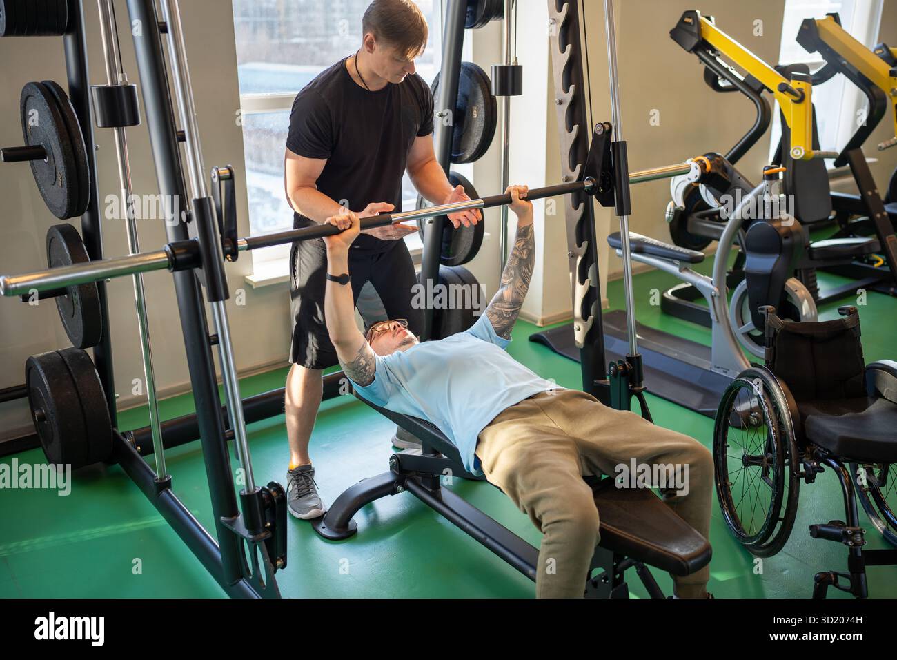 Atletico, attento e disabile su sedia a rotelle, lavora sulla forza del corpo, solleva il campanello in palestra con allenatore Foto Stock