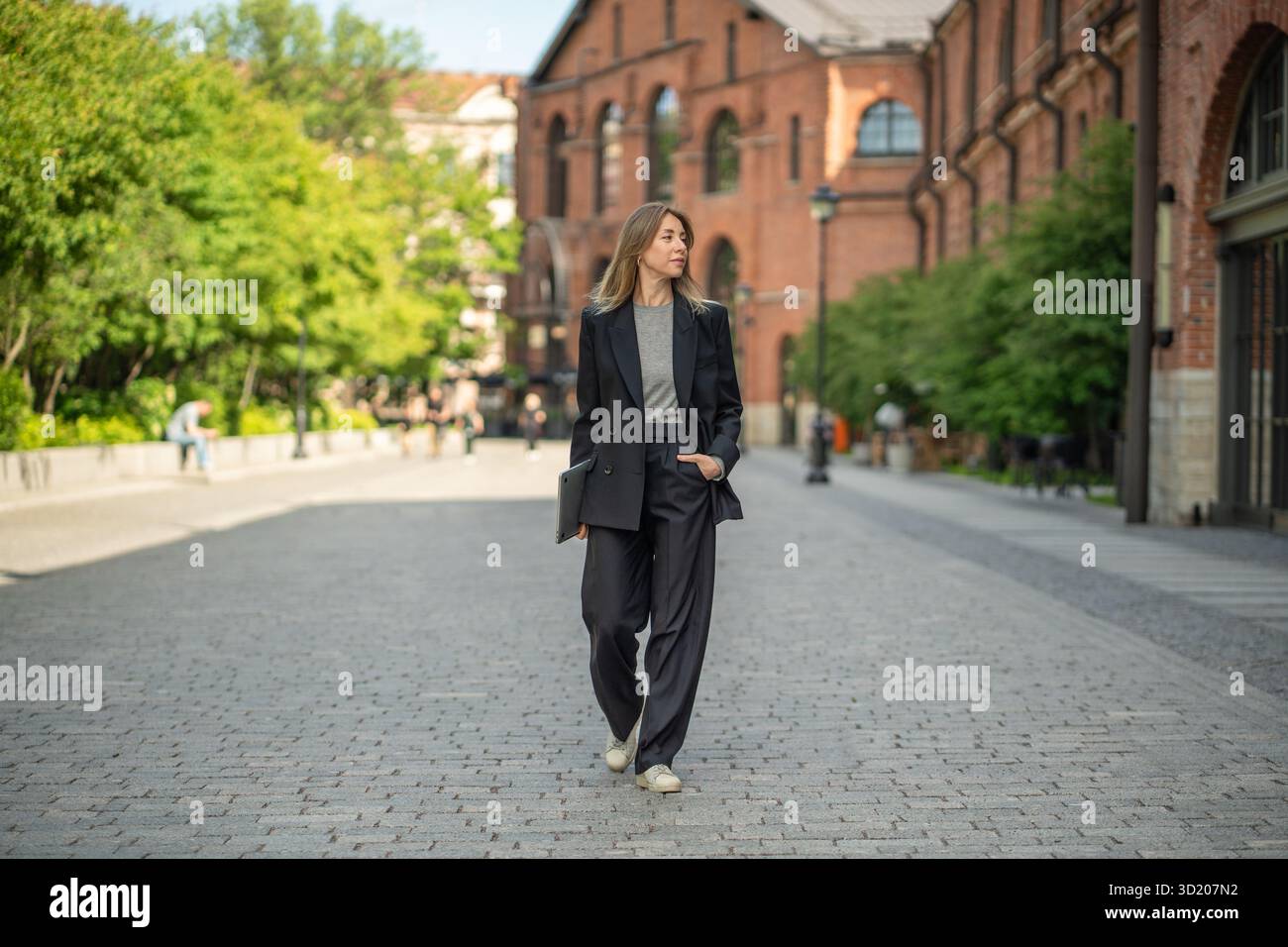 Elegante imprenditrice donna con laptop passeggia per le strade urbane, nomade digitale e freelance Foto Stock