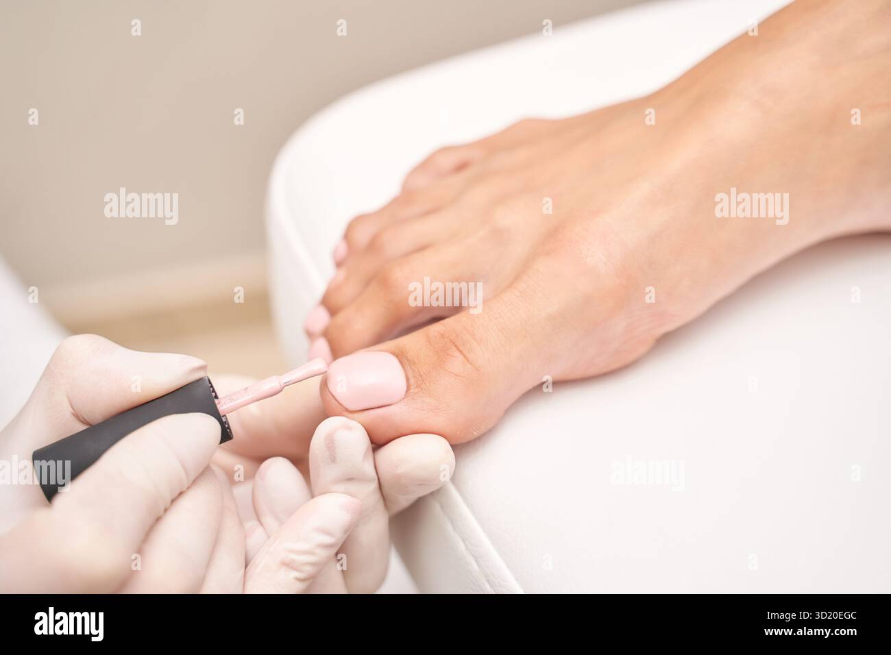 Pedicure femminile con smalto rosa sui piedi caucasici in salone Foto Stock