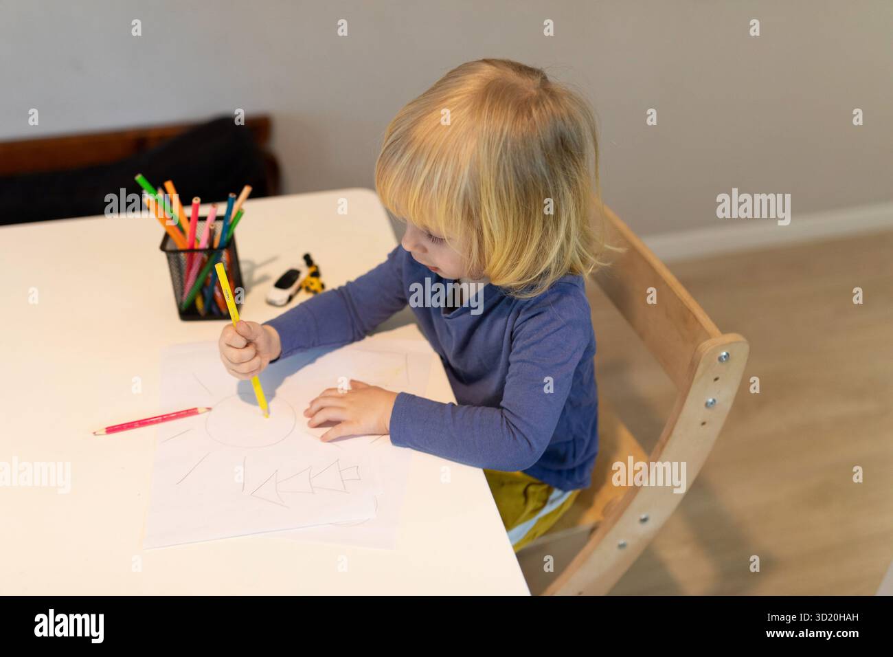 Bambino impegnato in attività creative di disegno in un luminoso spazio di lavoro interno durante il giorno Foto Stock