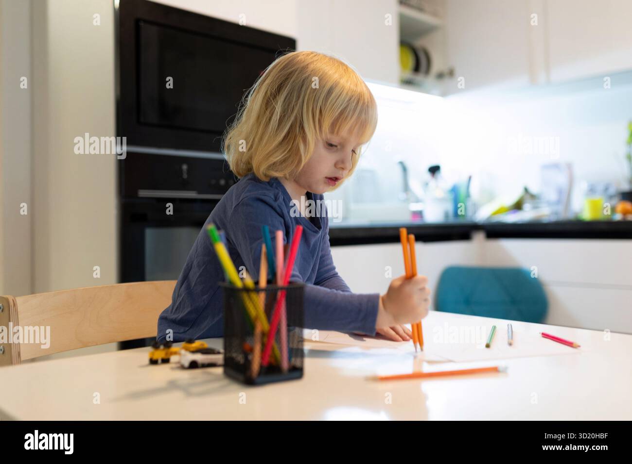 Bambino impegnato in attività creative di disegno a casa durante il giorno Foto Stock