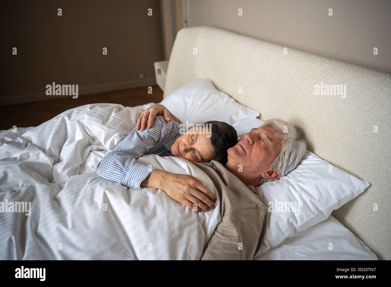 Una coppia matura serena e tranquilla che dorme abbracciandosi insieme in un comodo letto nella tranquilla camera da letto Foto Stock