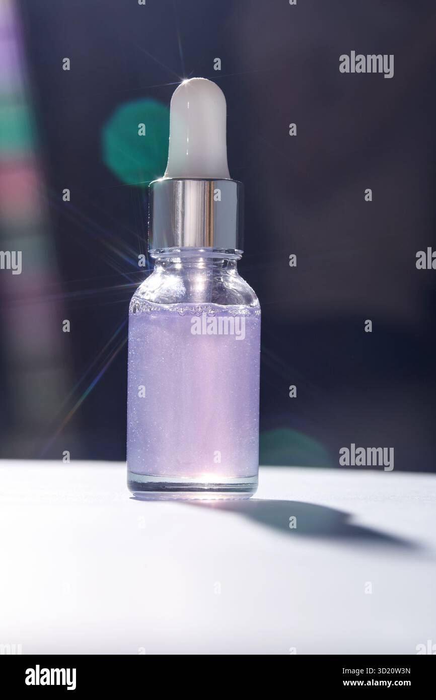Flacone luminoso di siero liquido viola con coperchio contagocce ed effetti di luce bokeh Foto Stock