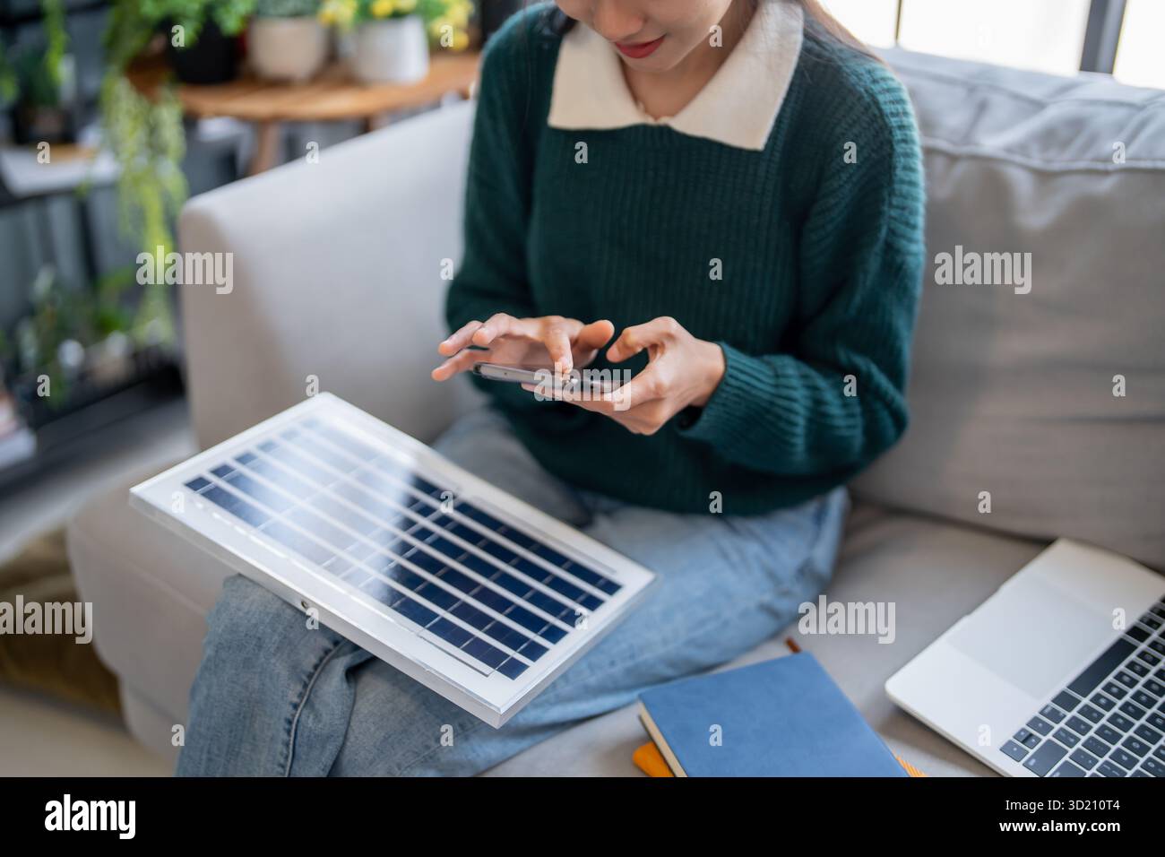 Donna asiatica che impara a conoscere le energie rinnovabili il controllo remoto dell'energia solare nella sua casa e l'installazione di pannelli solari sostenibili technolo Foto Stock
