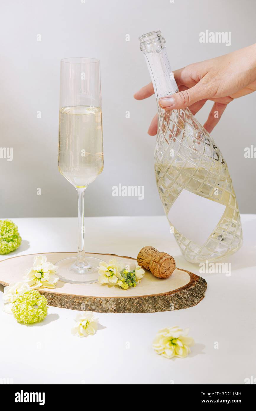 Elegante bevanda frizzante con fiori e sughero su una fetta di legno in un ambiente luminoso Foto Stock