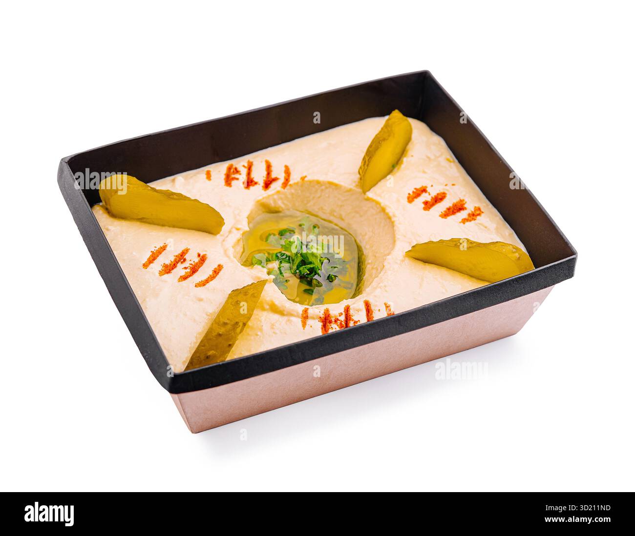 Hummus fatto in casa servito in un contenitore decorativo con sottaceti e guarnire per un gustoso antipasto o uno spuntino Foto Stock