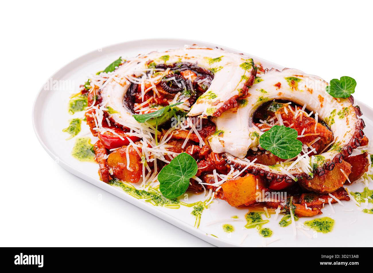 Tentacoli di polpo grigliato serviti con verdure arrostite ed erbe su un piatto bianco Foto Stock