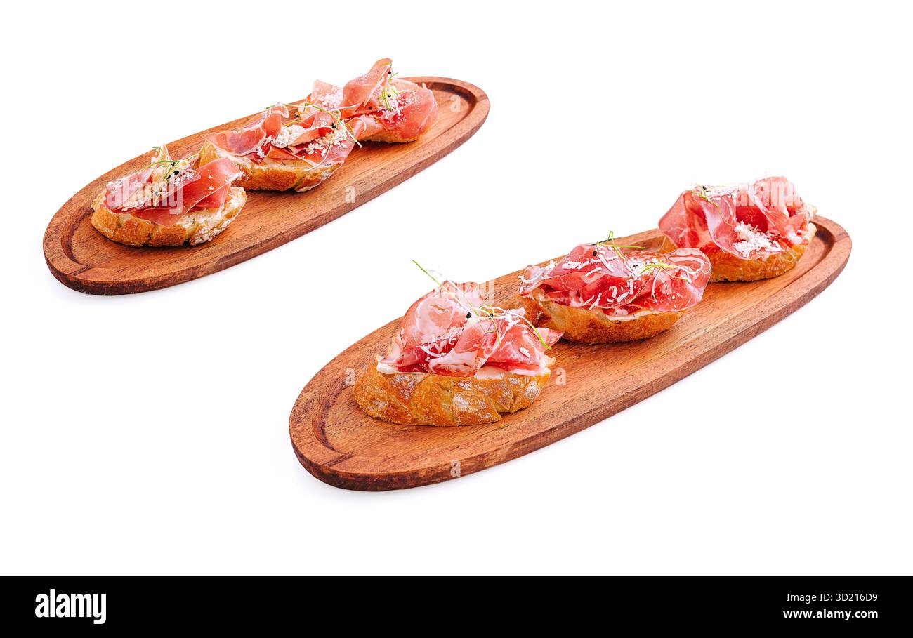 Piccoli assaggi di prosciutto stagionato sono serviti su due tavole di legno. La presentazione mette in evidenza la consistenza e i sapori del prosciutto, creando un'appe perfetta Foto Stock
