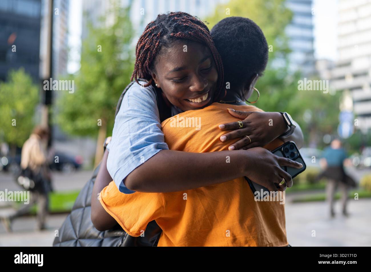 Donne afroamericane gioiose e allegre che abbracciano con amore, sorridono felicemente fuori di strada Foto Stock