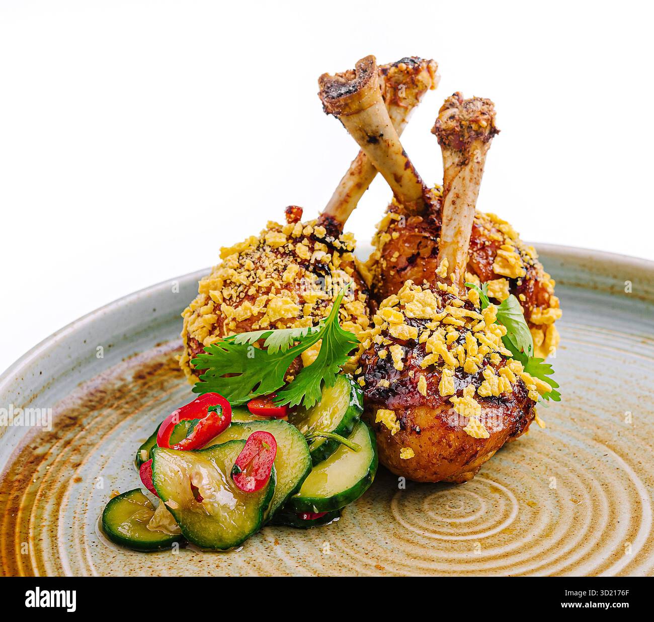 Cosce di pollo deliziosamente placcate con rivestimento croccante e insalata di cetrioli rinfrescante su un piatto rustico Foto Stock