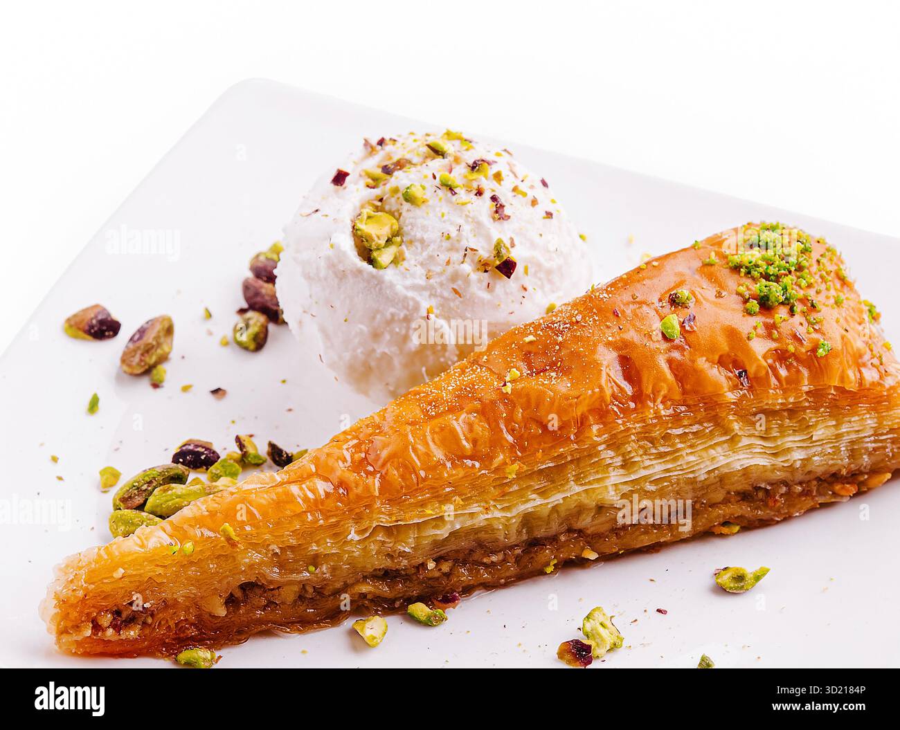 Delizioso dessert baklava servito con gelato e guarnizione di pistacchio su un piatto bianco Foto Stock