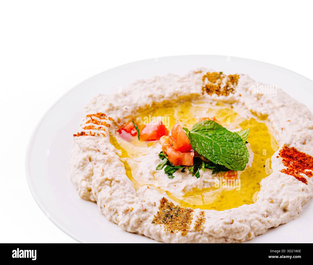 Salsa tahini ricca e cremosa servita con olio d'oliva, erbe aromatiche e spezie su un piatto bianco Foto Stock