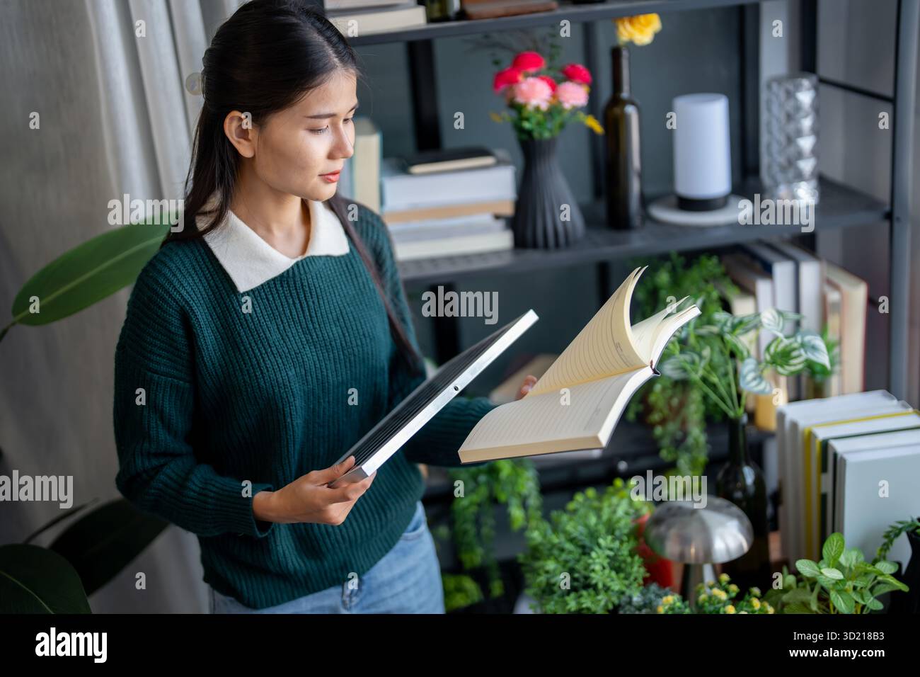 Donna asiatica che impara a conoscere le energie rinnovabili il controllo remoto dell'energia solare nella sua casa e l'installazione di pannelli solari sostenibili technolo Foto Stock