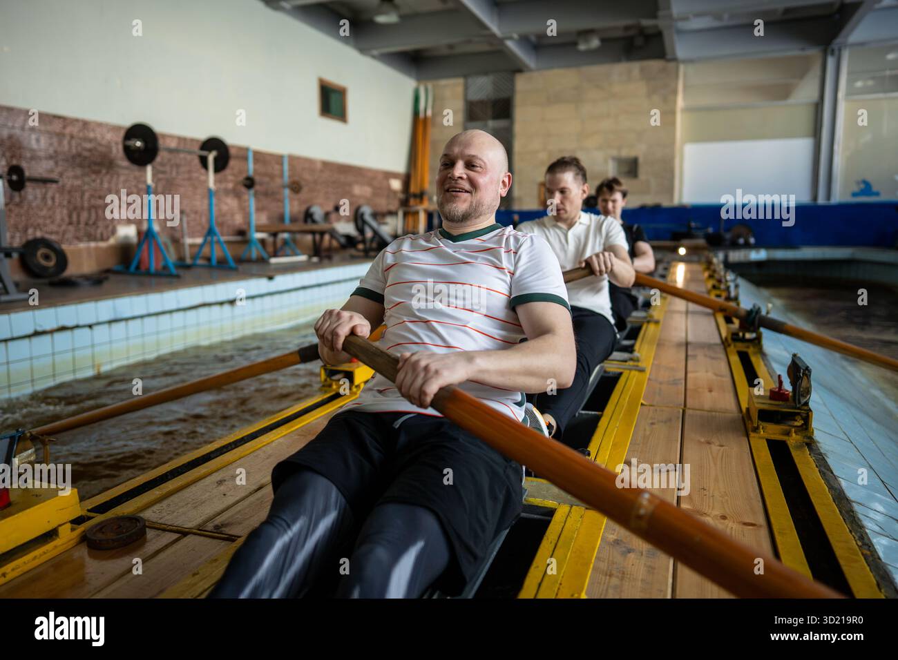 Gli atleti di canottaggio forzato si allenano intensamente sul simulatore di canottaggio durante l'allenamento di squadra sincronizzato Foto Stock