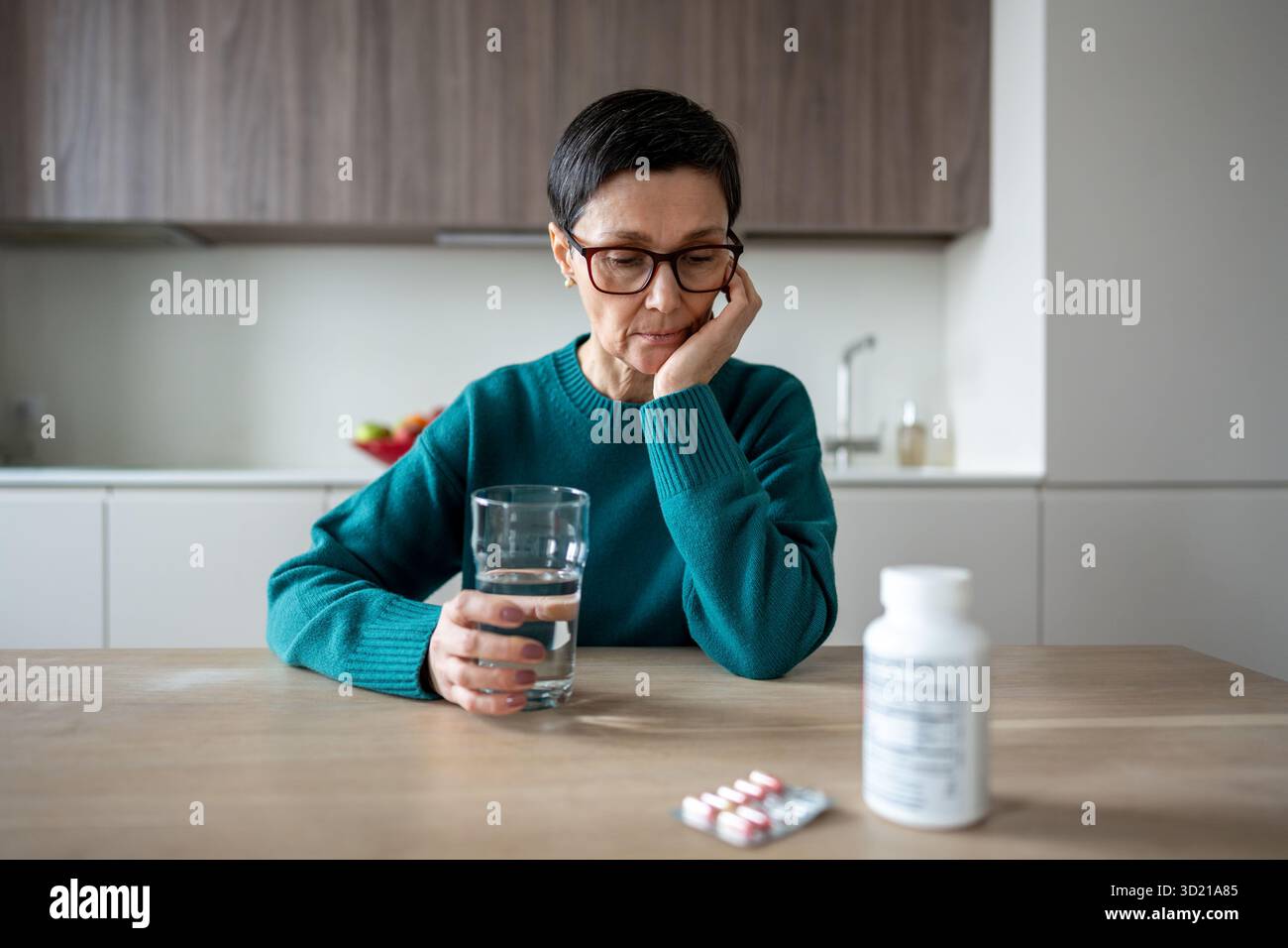 Donna solitaria apatica che guarda a farmaci che esitano sul dolore mentale e la battaglia emotiva Foto Stock