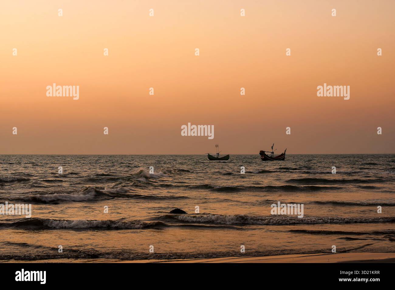 Tramonto tranquillo sulle onde oceaniche con barche sull'orizzonte Foto Stock