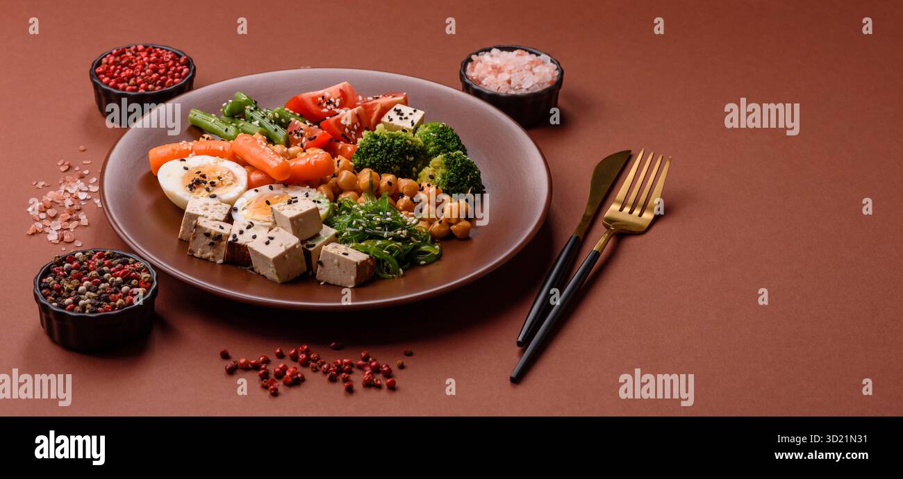 Insalata vegana, ciotole con ceci, broccoli, pomodori, formaggio tofu e uova sode Foto Stock