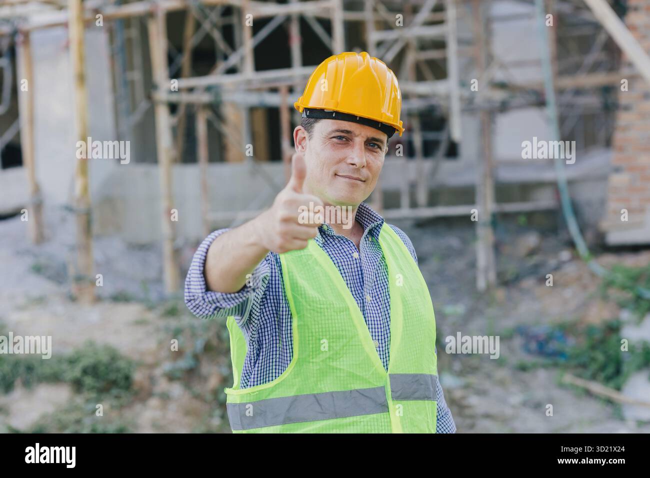 Felice ingegnere edile uomo caucasico, Smart Working con giubbotto riflettente di sicurezza pollice sicuro sorridere in cantiere all'aperto. Foto Stock