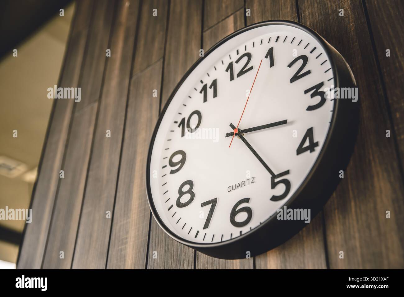 Time Clock appeso su un moderno sfondo in legno, orari di lavoro, orario di lavoro e orario di lavoro. Foto Stock