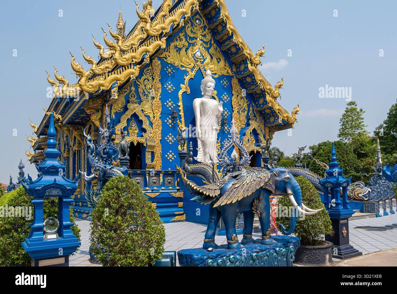 Wat Rong Suea Ten, noto anche come il Tempio Blu, mostra la sua vibrante architettura blu e oro con una statua bianca di Buddha e. Foto Stock