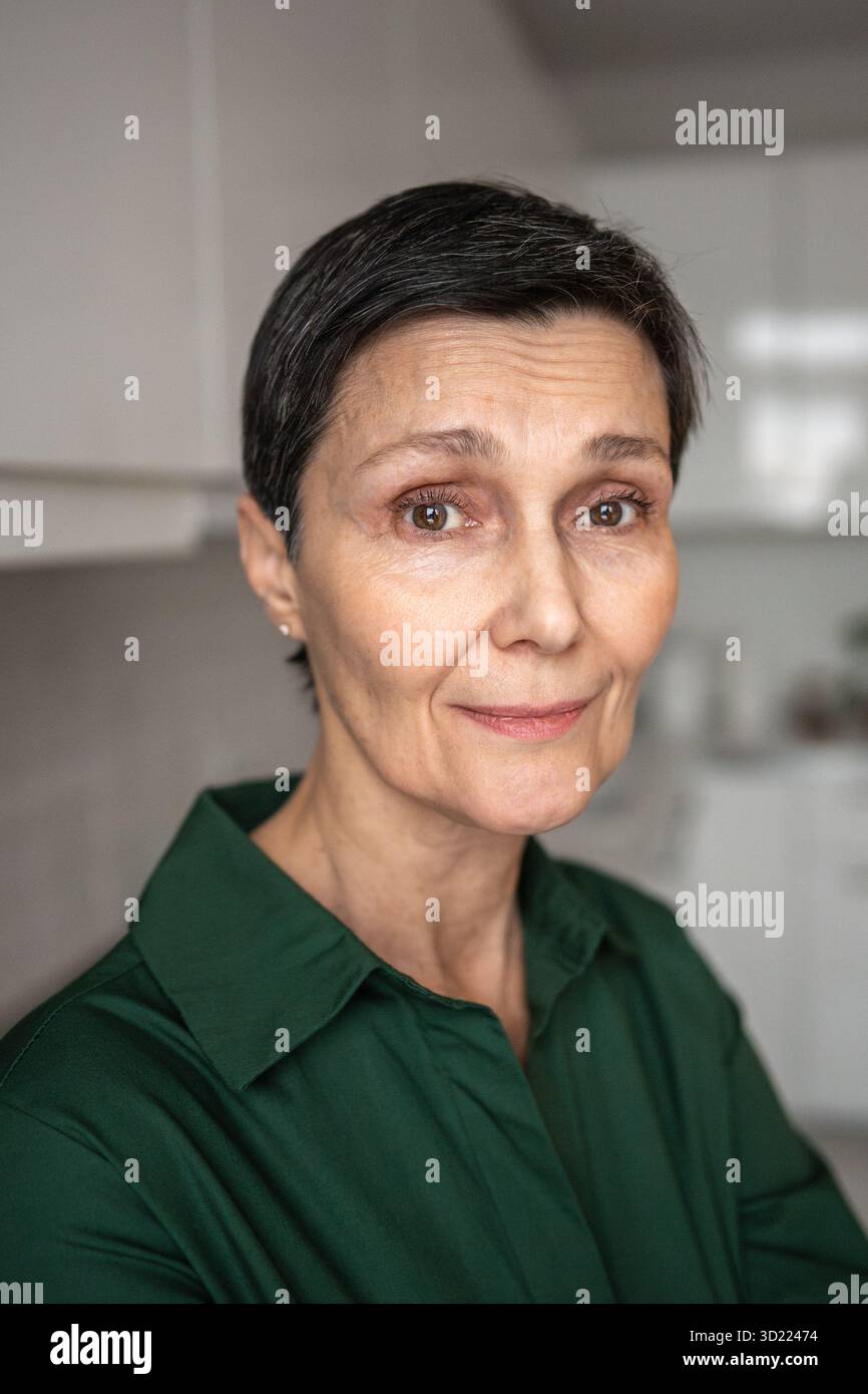 Donna matura sorridente e sicura di sé con uno sguardo caldo. Processo di invecchiamento, equilibrio emotivo, autoaccettazione Foto Stock