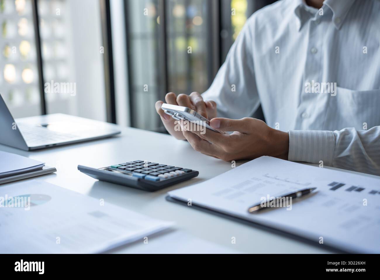 Uomo d'affari di successo che utilizza lo smartphone durante il lavoro in ufficio Foto Stock