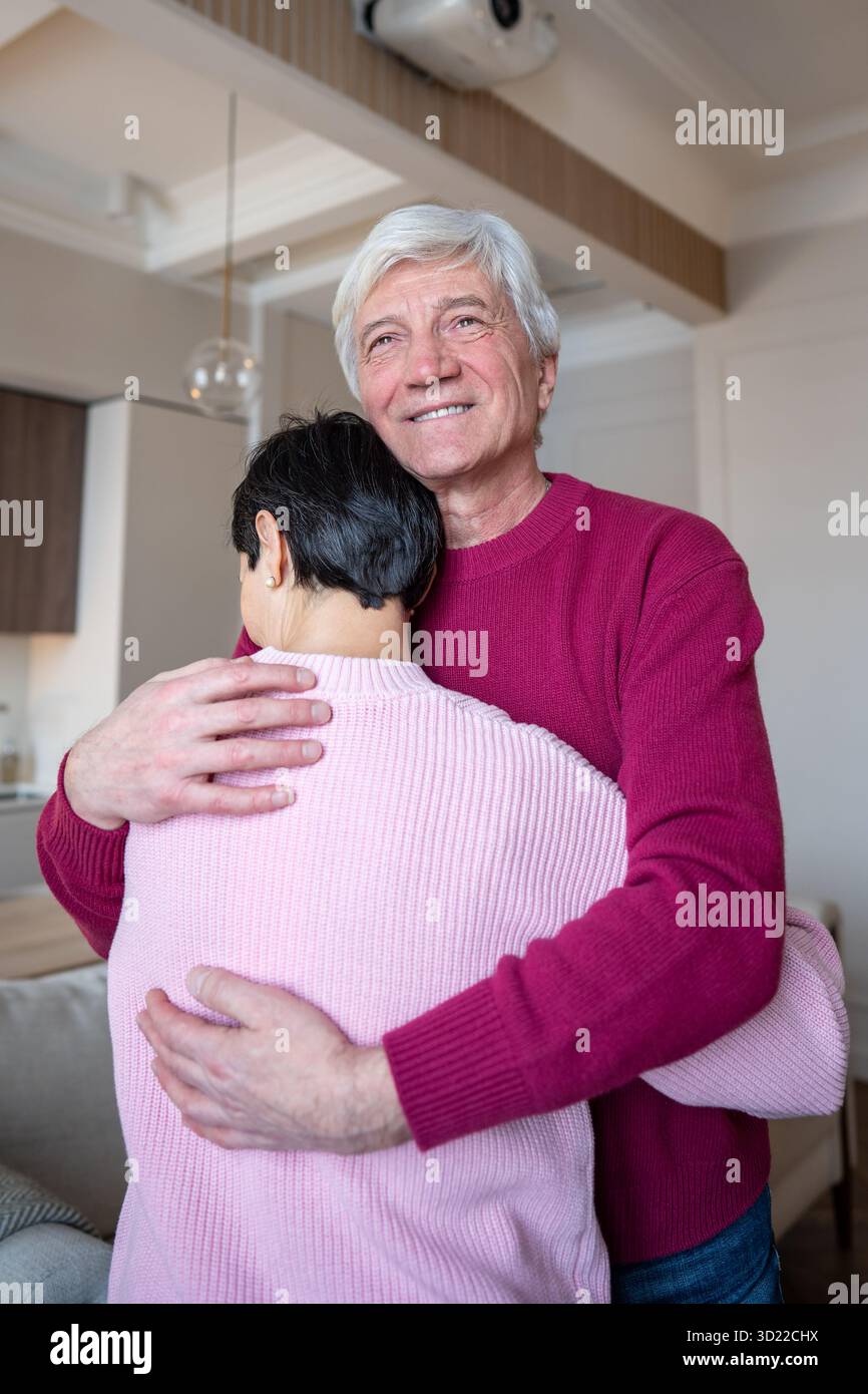 Sorridente uomo anziano che abbraccia la moglie consolante teneramente. Supporto per le relazioni di coppia, legame emotivo Foto Stock